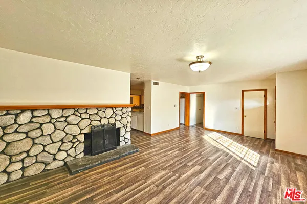 a view of an empty room with wooden floor and a fireplace
