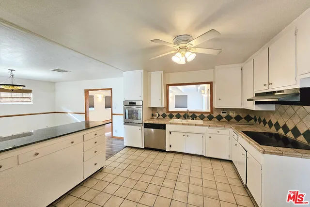 a kitchen with a sink a stove cabinets and a window
