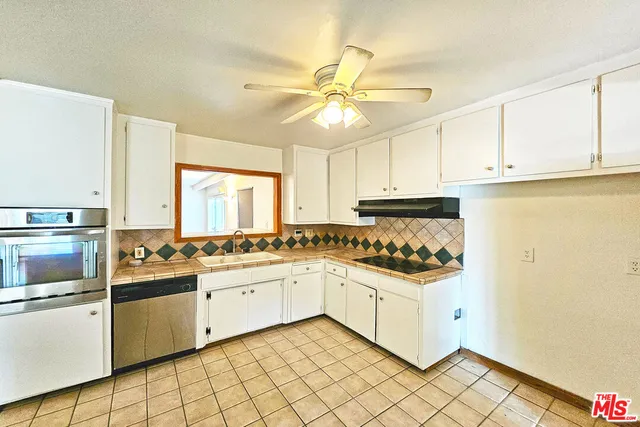 a kitchen with a stove a sink and white cabinets
