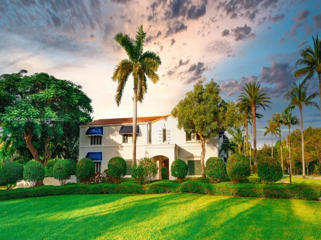 a front view of a house with a garden and trees
