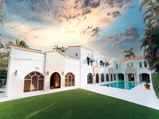 a view of a white house with a big yard and large trees