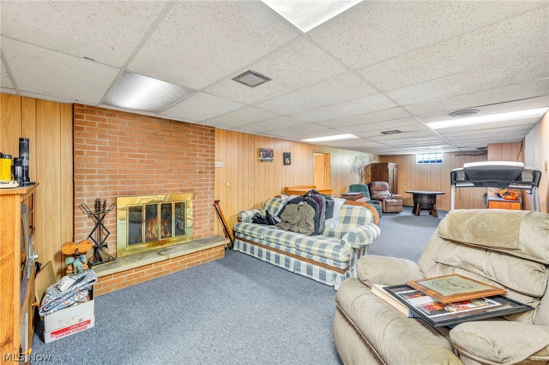1927 Connect Road Barberton, OH 44203 - Photo 23 of 28 Living room with wood walls, a drop ceiling, a brick fireplace, and brick wall