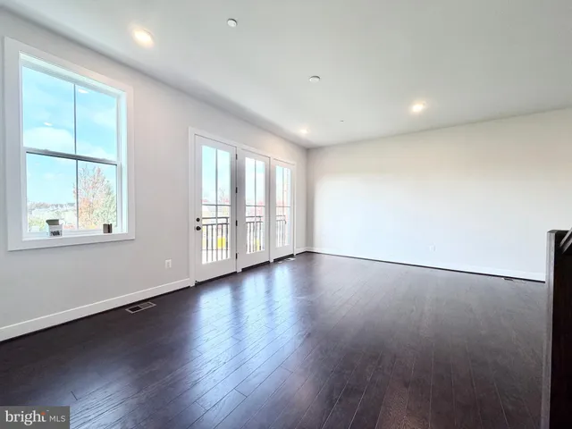 an empty room with wooden floor and windows with curtains