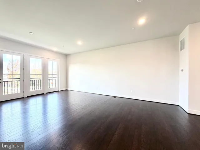 a view of an empty room with wooden floor and glass door