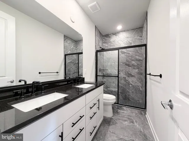 a bathroom with a sink a toilet a mirror and shower