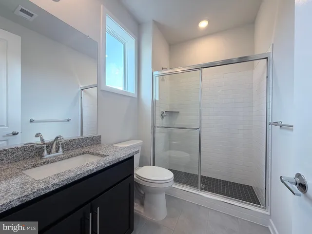 a bathroom with a granite countertop sink toilet and shower