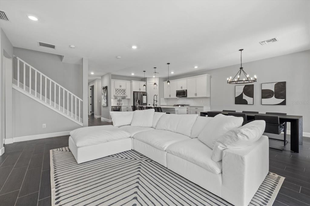 3508 Anchor Bay Trail Lakewood Ranch, FL 34211 - Photo 16 of 74 a living room with furniture a dining table and a chandelier