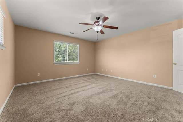 an empty room with windows and fan