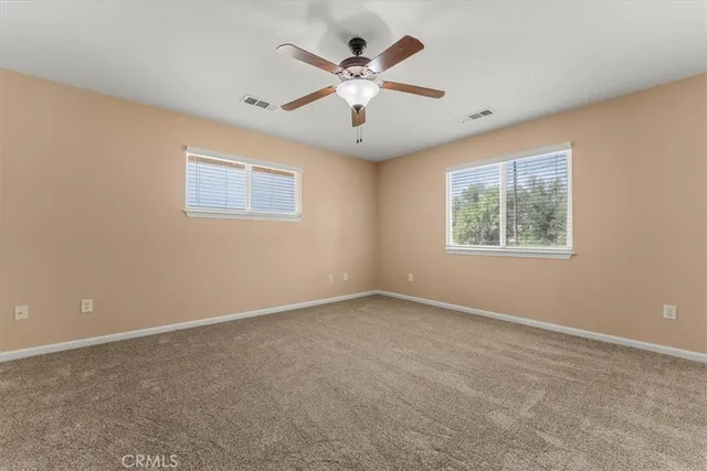 an empty room with windows and ceiling fan