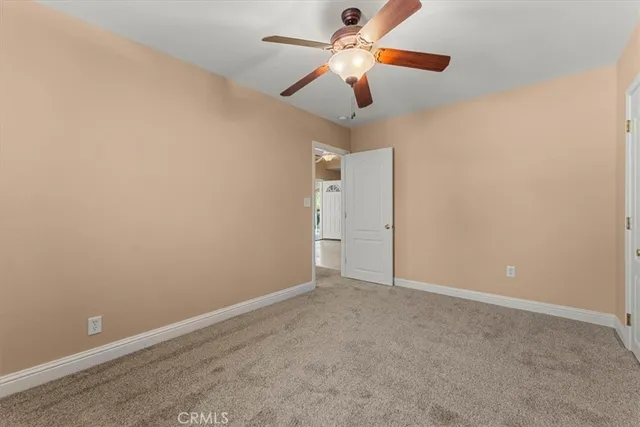 an empty room with a chandelier fan and a ceiling fan