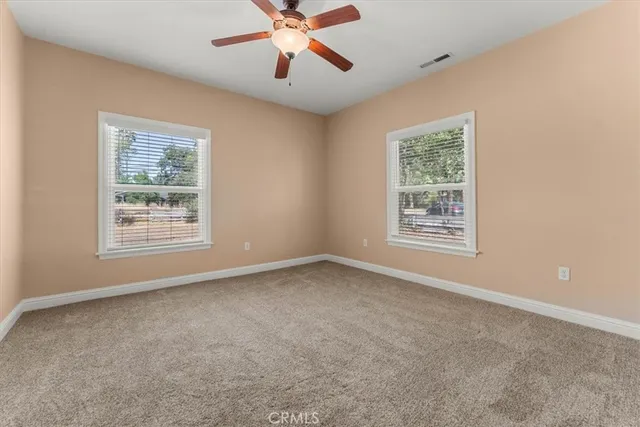 an empty room with windows and fan