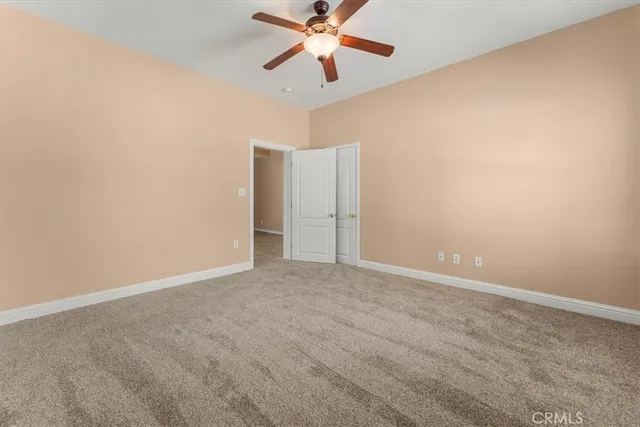 a view of an empty room and chandelier fan