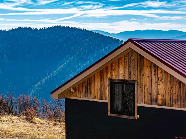 a view of wooden house with a yard in the background
