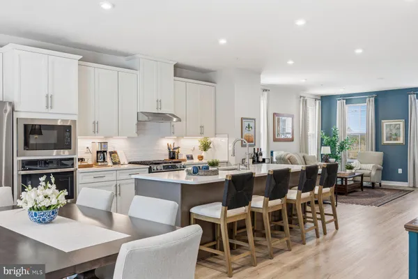 a kitchen with stainless steel appliances a white table chairs and a refrigerator