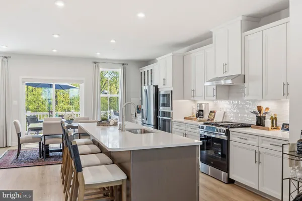 a dining room with stainless steel appliances kitchen island granite countertop a dining table chairs and a refrigerator