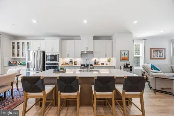 a dining room with stainless steel appliances kitchen island granite countertop a dining table chairs and a refrigerator