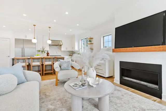 a living room with furniture a flat screen tv and kitchen view