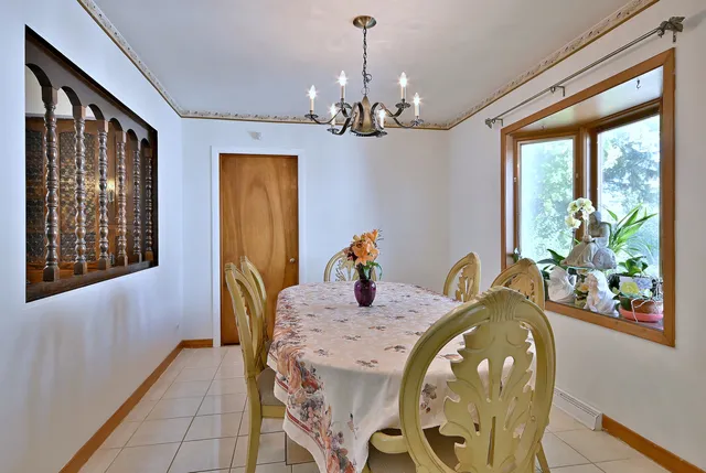 a dining room with chandelier and wooden floor
