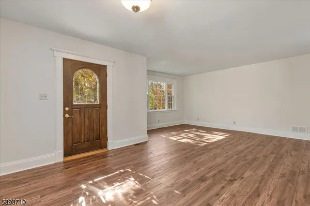 an empty room with wooden floor closet and windows