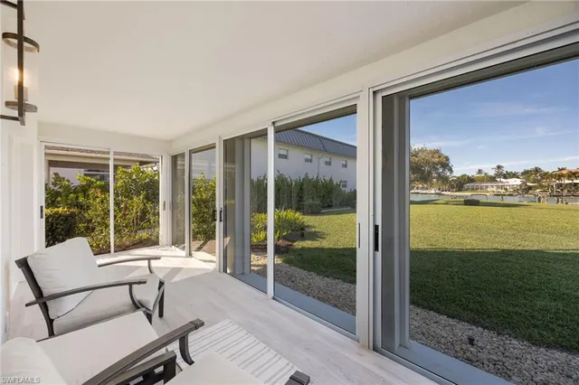 a living room with patio furniture and floor to ceiling window