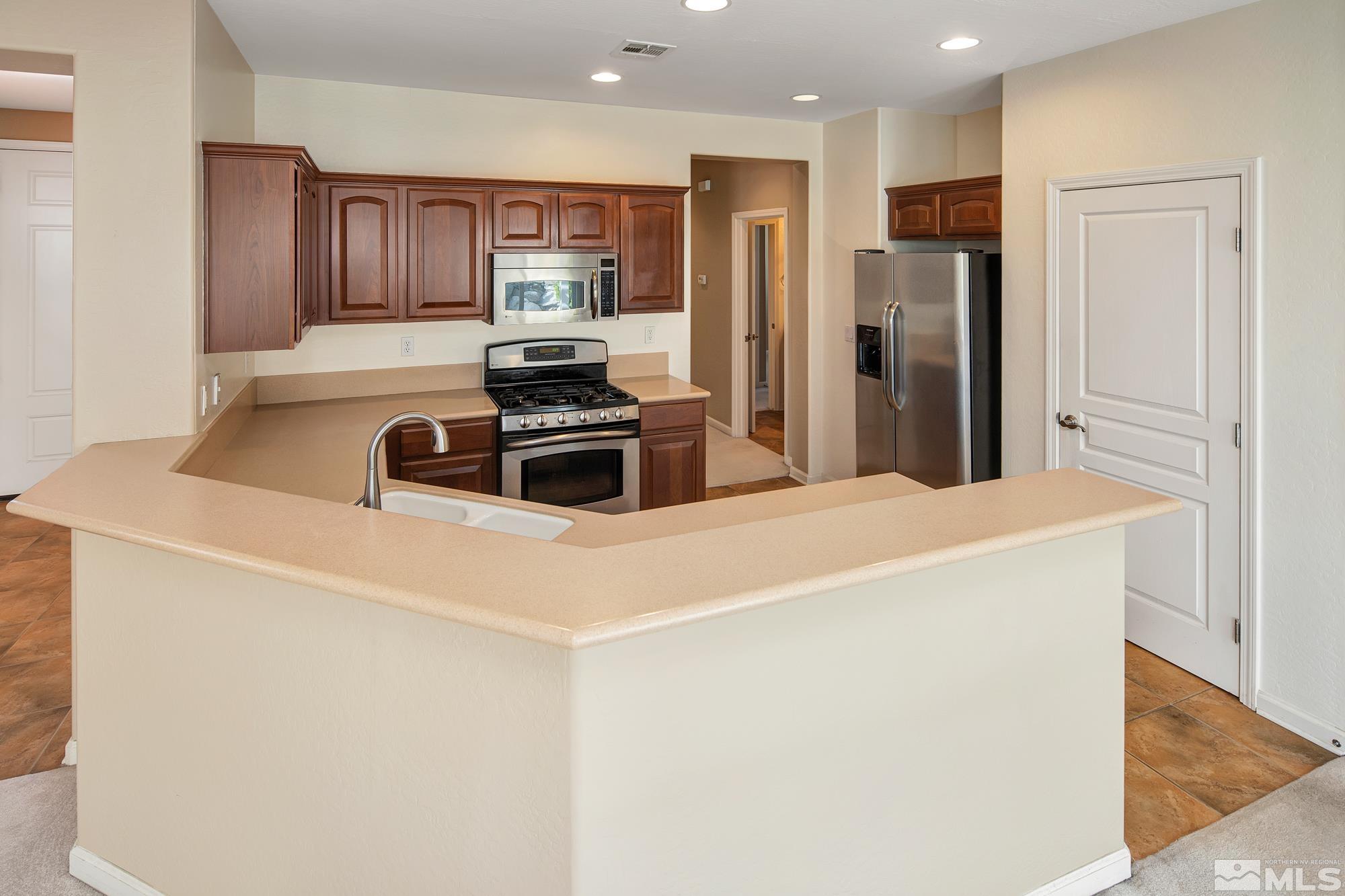 1180 Meridian Ranch Drive Reno, NV 89523 - Photo 7 of 28 a kitchen with stainless steel appliances a refrigerator stove microwave and sink