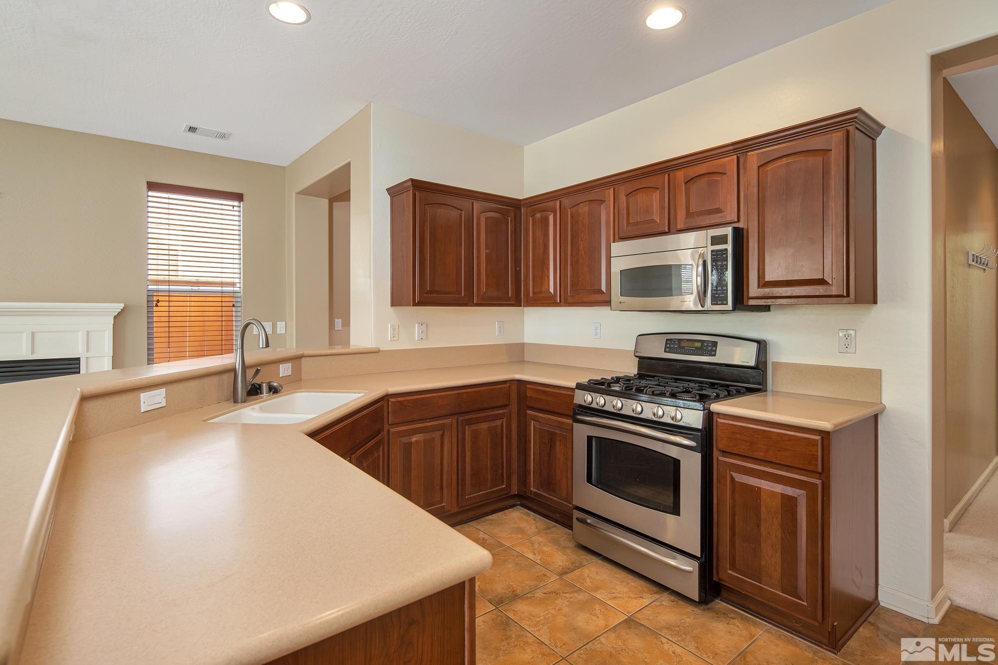 1180 Meridian Ranch Drive Reno, NV 89523 - Photo 9 of 28 a kitchen with stainless steel appliances granite countertop a sink stove and microwave