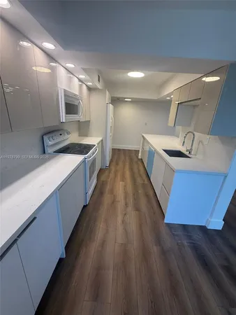 a large kitchen with wooden floor and stainless steel appliances