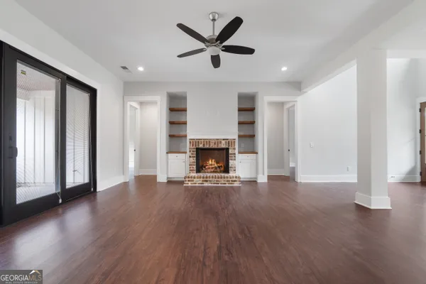 an empty room with wooden floor a fireplace and windows
