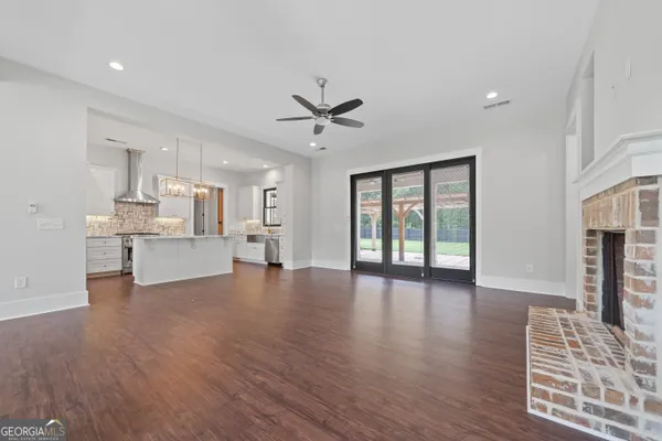 a view of an empty room with wooden floor and a kitchen