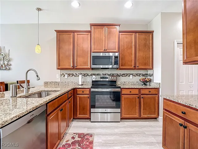 a kitchen with stainless steel appliances granite countertop a stove a sink dishwasher and a microwave oven with wooden floor