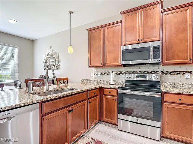 a kitchen with granite countertop a sink stove and microwave