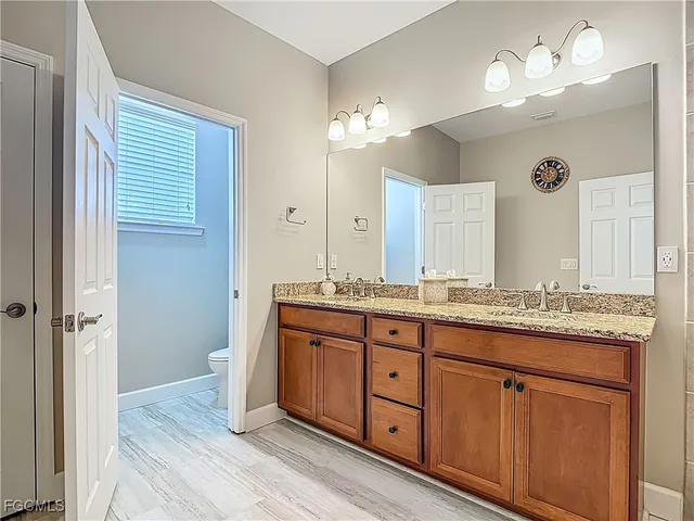 a bathroom with a granite countertop double vanity sink and a mirror