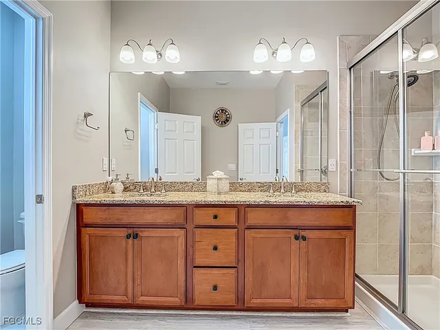 a bathroom with a granite countertop sink a large mirror and a toilet