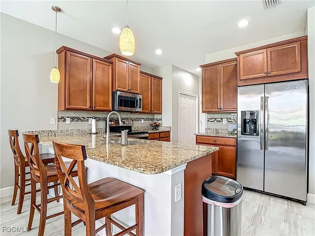 a kitchen with granite countertop a table chairs microwave and refrigerator