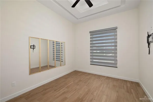 a view of an empty room with a window and wooden floor