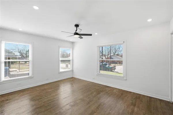 a view of an empty room with a window and wooden floor