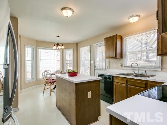 5709 Edgebury Road Raleigh, NC 27613 - Photo 9 of 20 a kitchen with a sink a stove and chairs with wooden floor