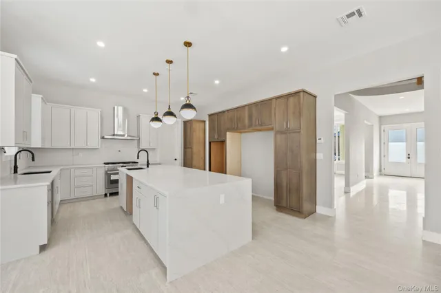 a large white kitchen with a refrigerator a sink dishwasher a stove and a dining table with wooden cabinet