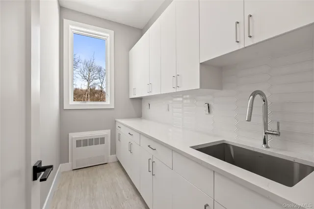 a kitchen with white cabinets and sink