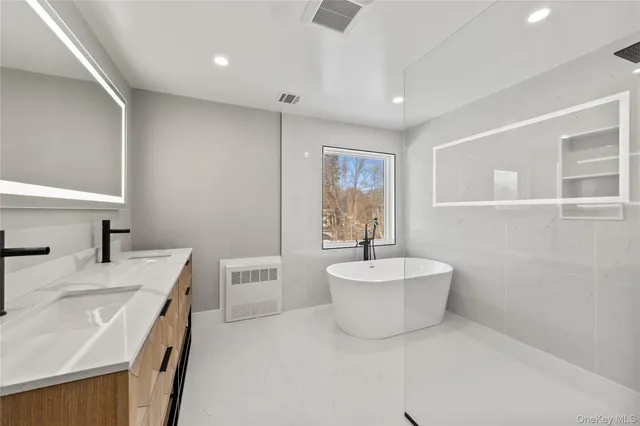 a bathroom with a double vanity sink mirror and bathtub