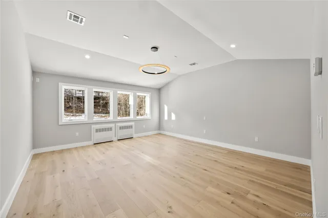 a view of an empty room with wooden floor and windows