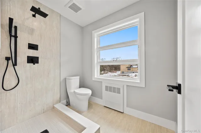 a bathroom with a toilet sink a shower and a window