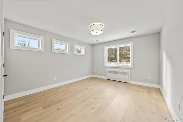 a view of an empty room with a window and wooden floor