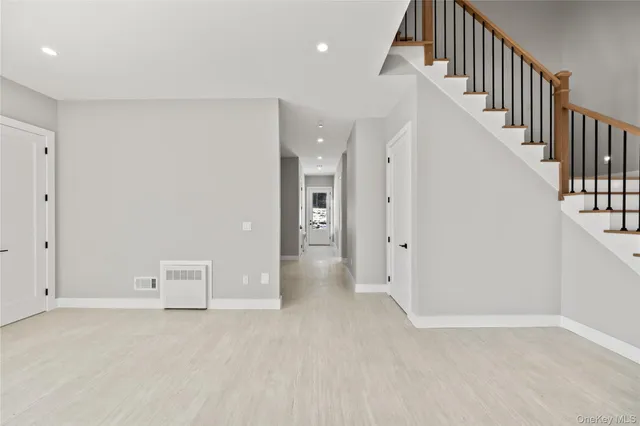 a view of an empty room with wooden floor and stairs
