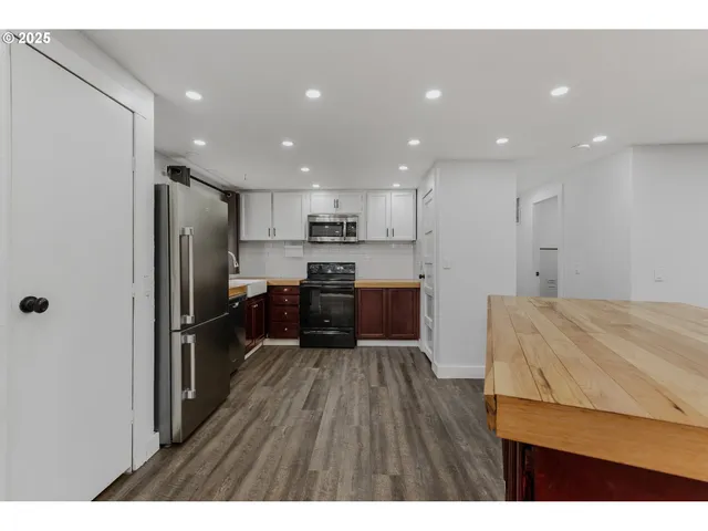 a kitchen with kitchen island wooden floors appliances and cabinets