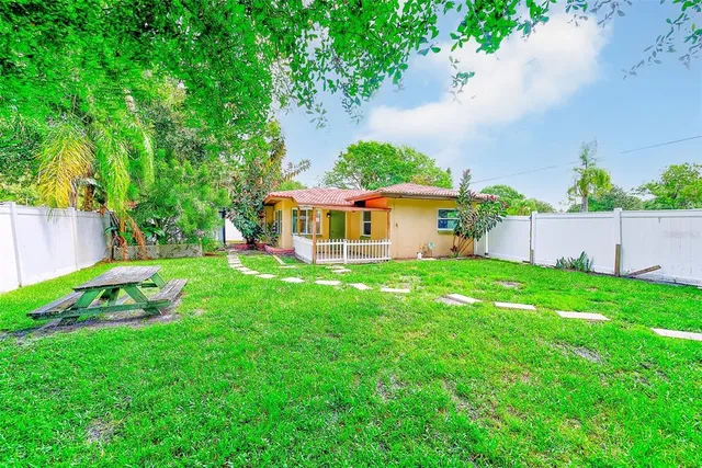 a view of house with a big yard and large trees