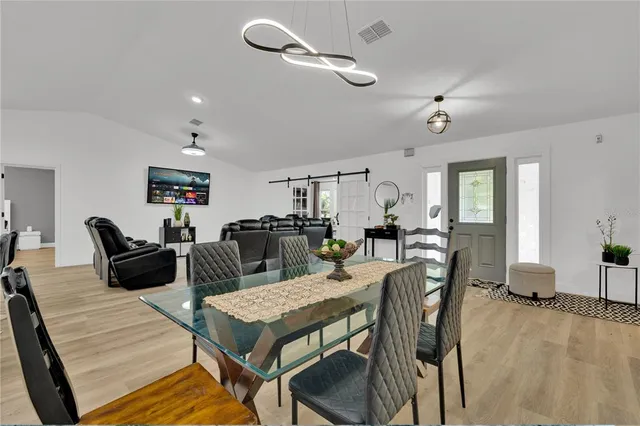 a kitchen with stainless steel appliances kitchen island granite countertop a stove a sink a microwave a dining table and chairs with wooden floor