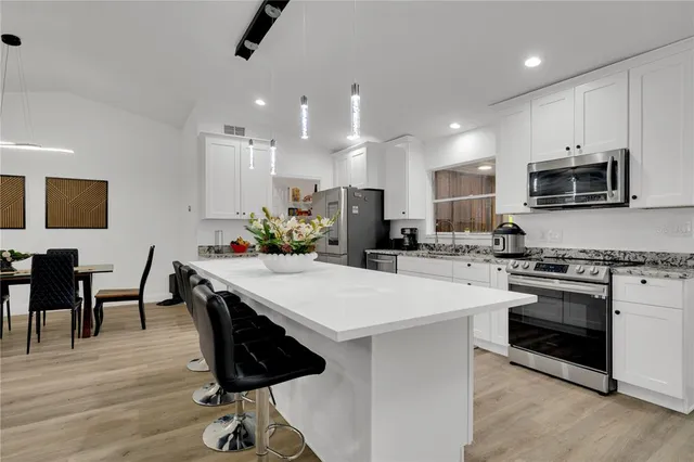 a large white kitchen with a sink and white cabinets