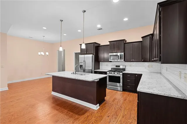 a kitchen with stainless steel appliances granite countertop a refrigerator a oven and a sink