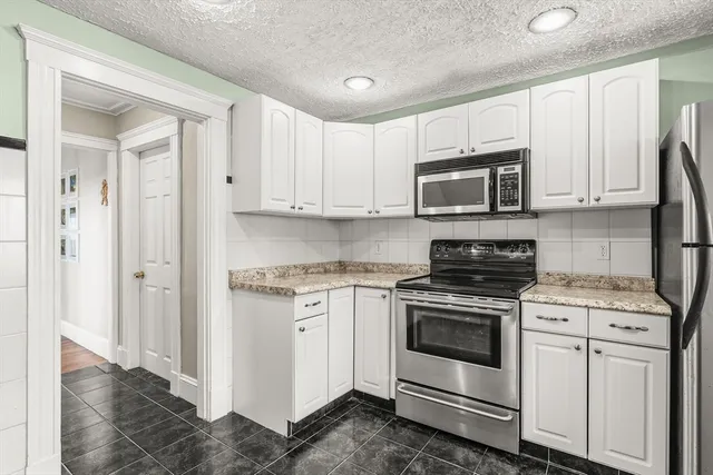 a kitchen with stainless steel appliances granite countertop a stove a microwave and a white cabinets